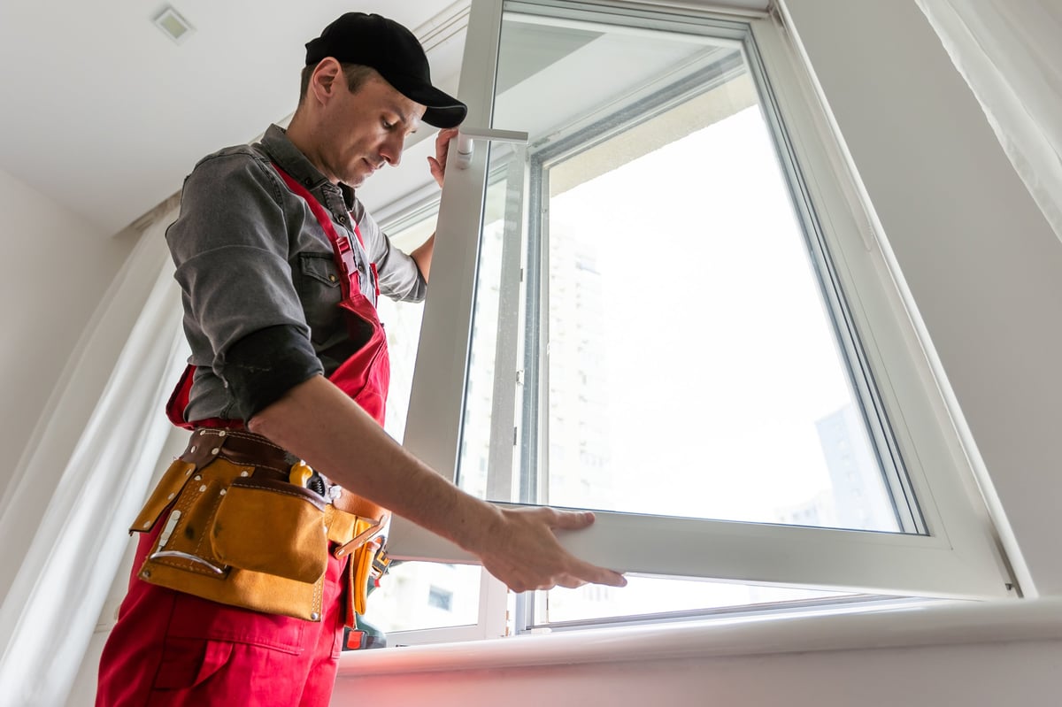 Worker mounting a new window into a prepared opening during a home renovation