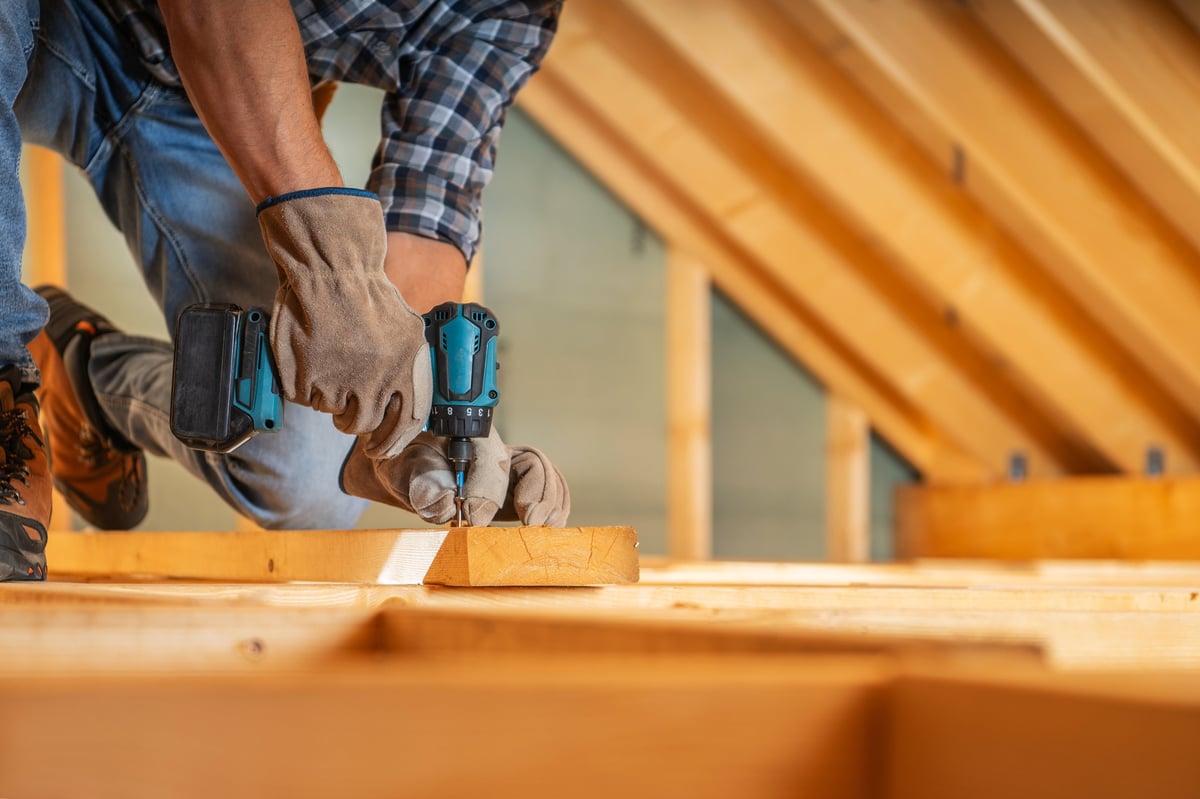 Skilled carpenter using a power drill to secure wooden beams during a project